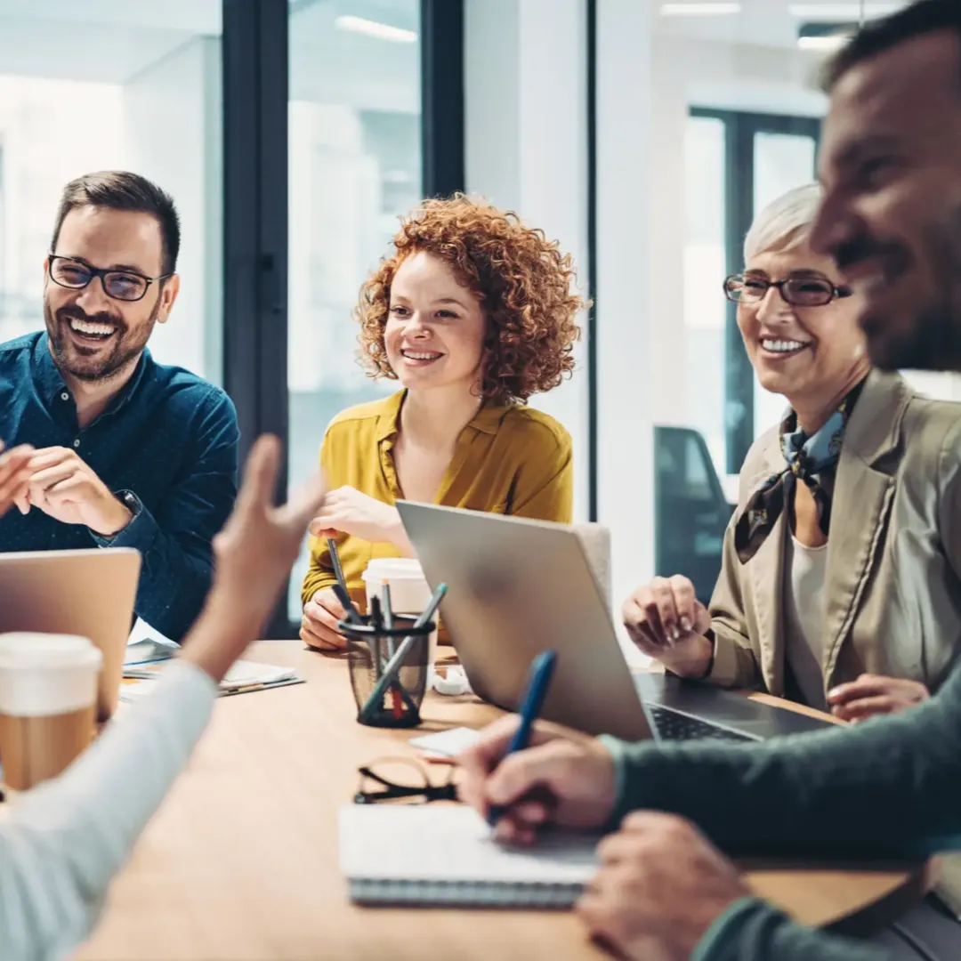 A group of colleagues happily collaborating in an office meeting.