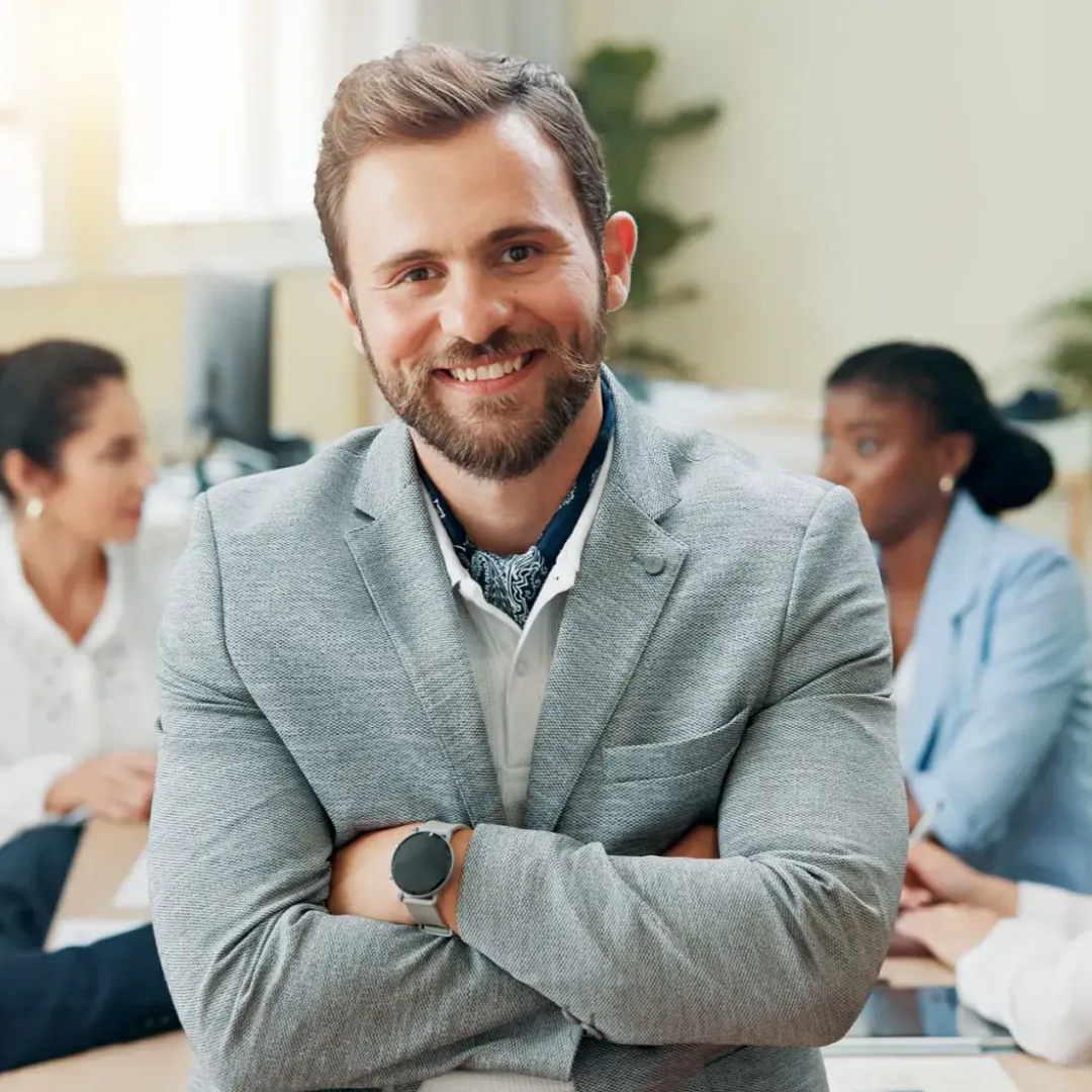 Confident businessman smiling with colleagues in background.