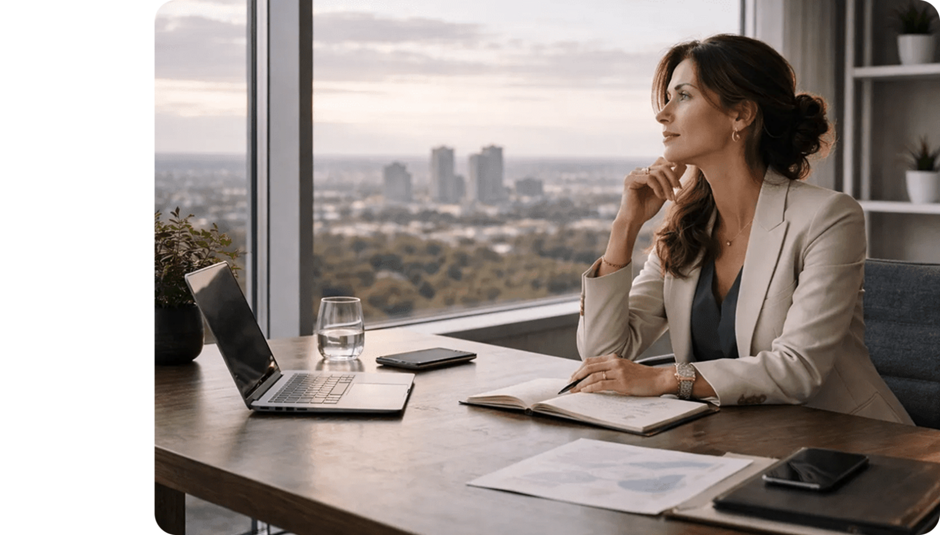 Woman thoughtfully looking out a large office window with cityscape view.